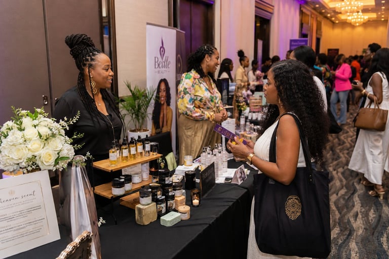 Woman browsing beauty products at vendor booth during indoor event with attendees in background
